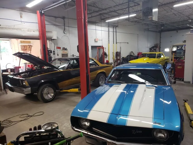 Classic muscle cars on lifts inside the Pembroke Radiator shop